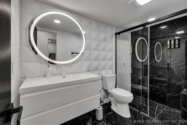 bathroom with an enclosed shower, vanity, tile walls, and toilet