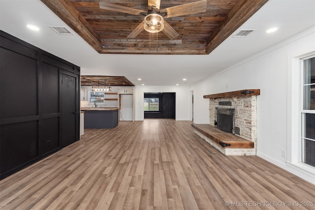 unfurnished living room featuring a tray ceiling, a fireplace, and light hardwood / wood-style floors