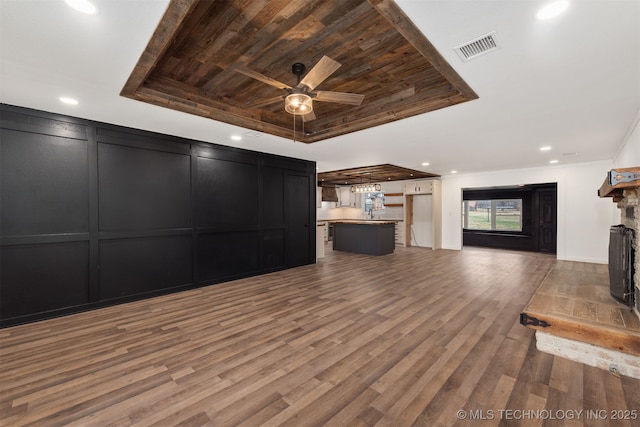 unfurnished living room featuring wood ceiling, ornamental molding, a tray ceiling, ceiling fan, and hardwood / wood-style floors