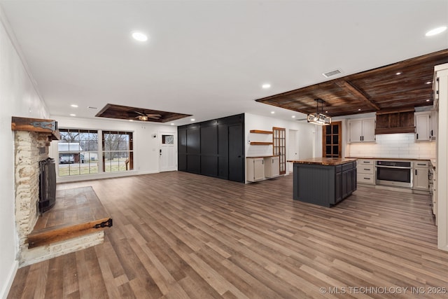 kitchen with stainless steel oven, wood-type flooring, a tray ceiling, and a center island