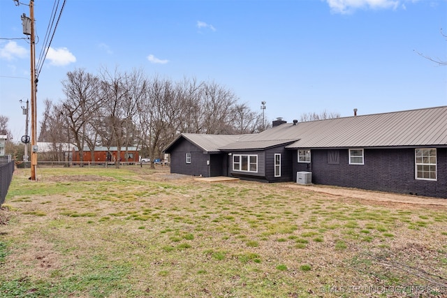 back of property featuring central AC unit and a lawn