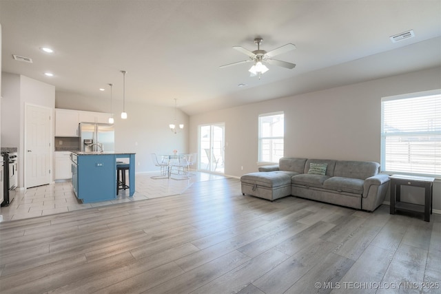 living room with vaulted ceiling, ceiling fan, and light hardwood / wood-style flooring