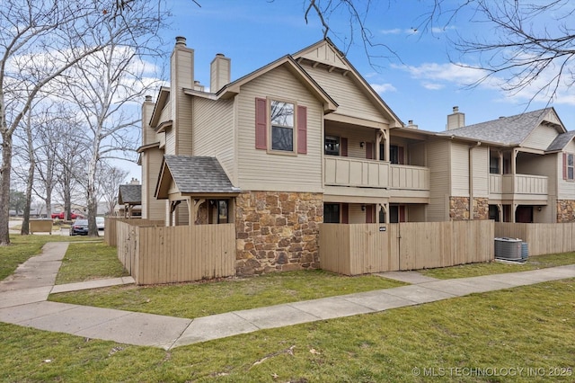 view of front of property featuring central AC, a balcony, and a front lawn