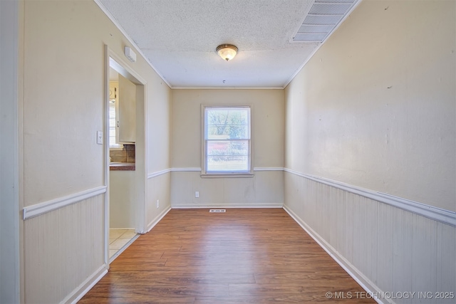 unfurnished room with crown molding, hardwood / wood-style flooring, and a textured ceiling