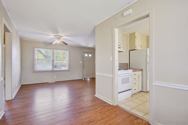 interior space featuring crown molding, ceiling fan, and light wood-type flooring