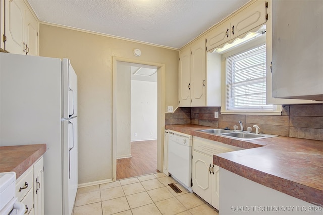 kitchen featuring sink, white appliances, tasteful backsplash, a textured ceiling, and light tile patterned flooring