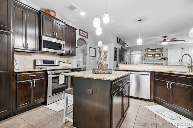 kitchen featuring pendant lighting, sink, appliances with stainless steel finishes, dark brown cabinets, and a center island