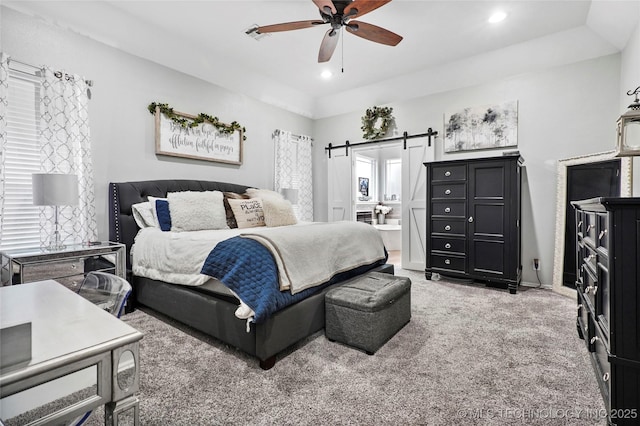 bedroom with a barn door, carpet floors, connected bathroom, and ceiling fan