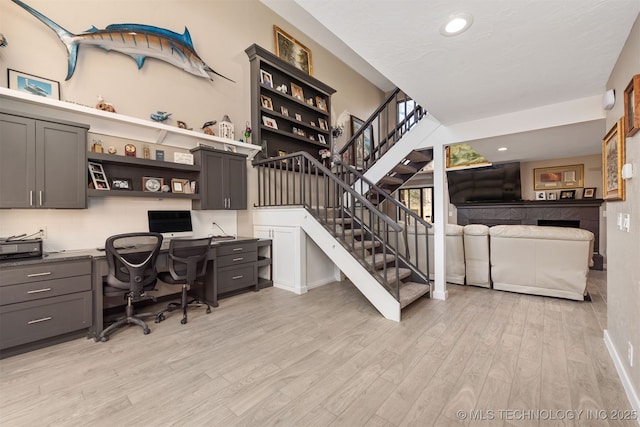 office space with built in desk and light hardwood / wood-style floors