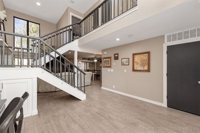 interior space with wood-type flooring, a towering ceiling, and ceiling fan