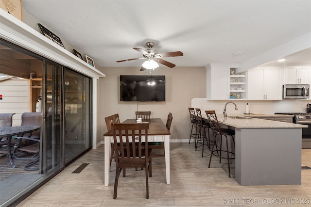 dining space with ceiling fan, sink, and light hardwood / wood-style flooring