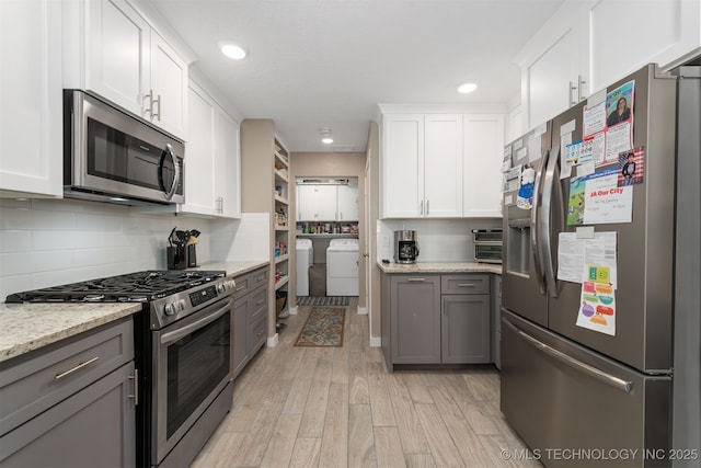 kitchen featuring white cabinetry, appliances with stainless steel finishes, gray cabinetry, and light stone counters