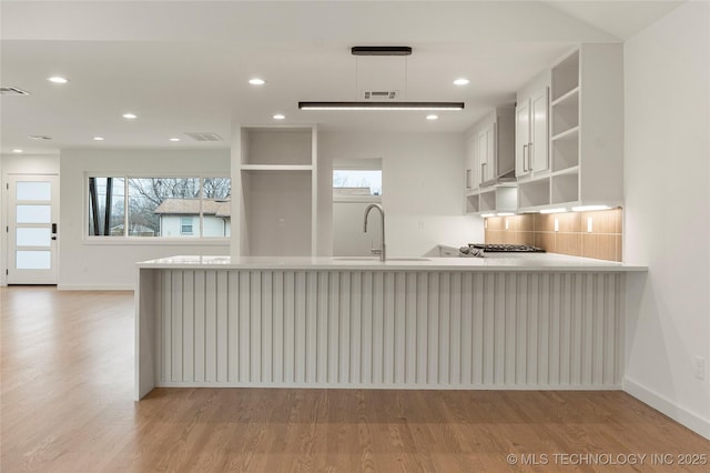 kitchen featuring plenty of natural light, sink, light hardwood / wood-style flooring, and kitchen peninsula