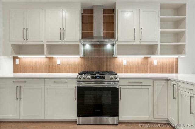 kitchen with white cabinets, stainless steel gas range, decorative backsplash, and wall chimney range hood