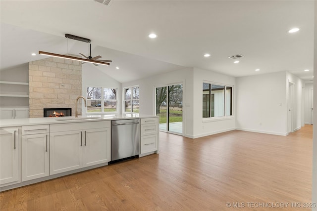 kitchen featuring sink, white cabinetry, light wood-type flooring, a large fireplace, and dishwasher