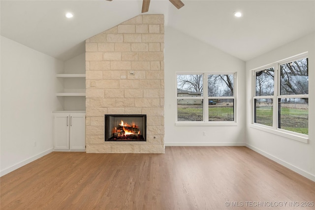 unfurnished living room with vaulted ceiling, light hardwood / wood-style flooring, built in features, ceiling fan, and a fireplace