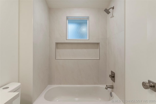 bathroom with toilet and tiled shower / bath