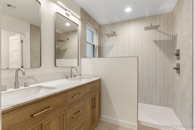 bathroom with a tile shower, vanity, and tile patterned flooring