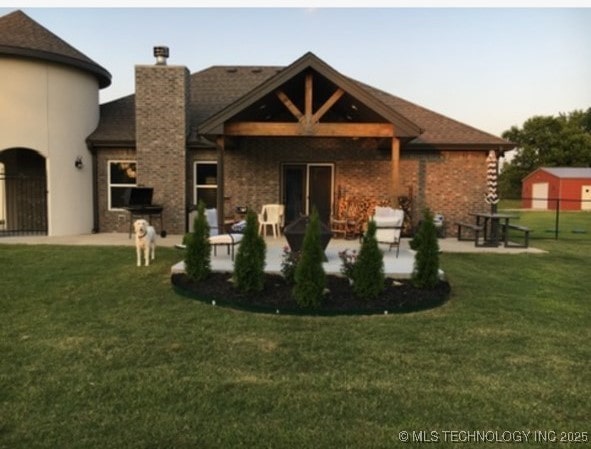 back house at dusk featuring a patio and a lawn