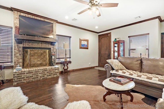 living room with dark wood-type flooring, ceiling fan, crown molding, and a brick fireplace