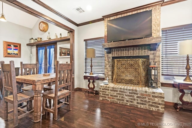 dining area featuring ornamental molding, wood-type flooring, a brick fireplace, and plenty of natural light