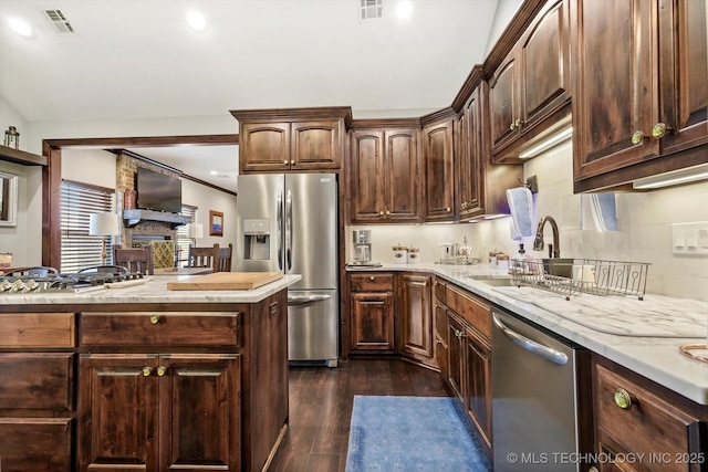 kitchen featuring sink, dark brown cabinets, stainless steel appliances, dark hardwood / wood-style floors, and decorative backsplash