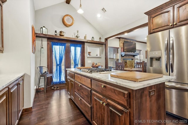 kitchen with vaulted ceiling with beams, hanging light fixtures, stainless steel appliances, dark hardwood / wood-style floors, and a center island