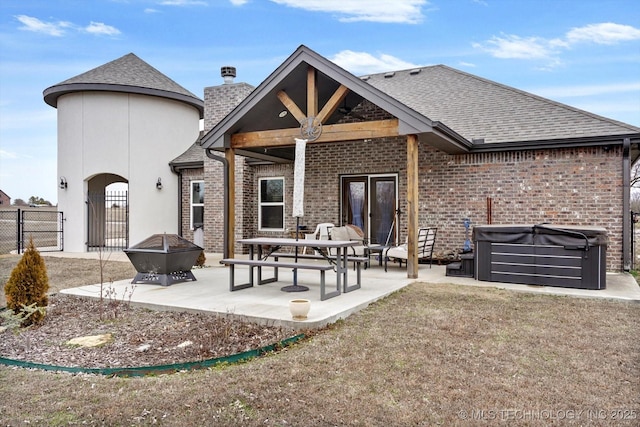 rear view of house with a patio area, a hot tub, and an outdoor fire pit