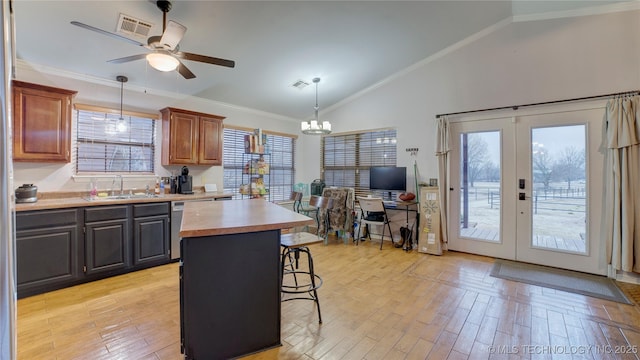 kitchen with sink, a breakfast bar, hanging light fixtures, a kitchen island, and french doors