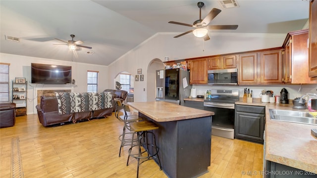 kitchen with sink, a center island, vaulted ceiling, appliances with stainless steel finishes, and ceiling fan