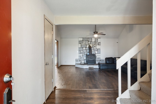 entryway featuring ceiling fan, dark hardwood / wood-style flooring, vaulted ceiling, and a wood stove