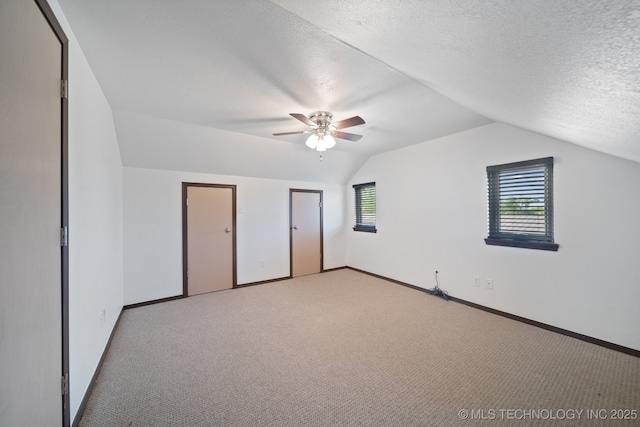 bonus room featuring ceiling fan, light colored carpet, vaulted ceiling, and a textured ceiling