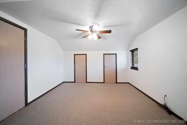 unfurnished bedroom featuring ceiling fan, light colored carpet, and lofted ceiling