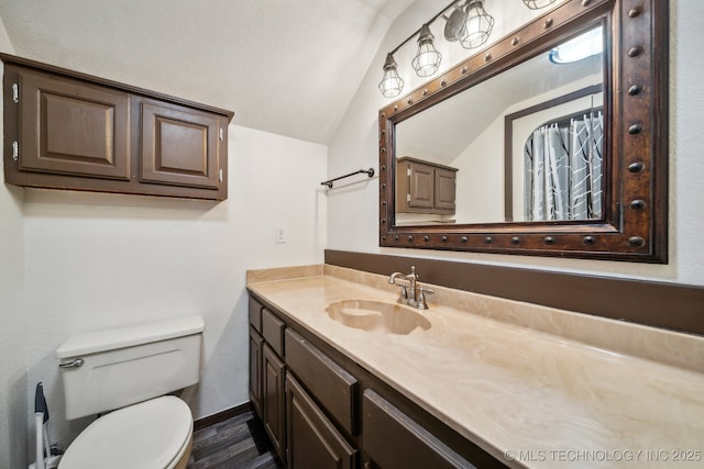 bathroom with lofted ceiling, toilet, wood-type flooring, and vanity