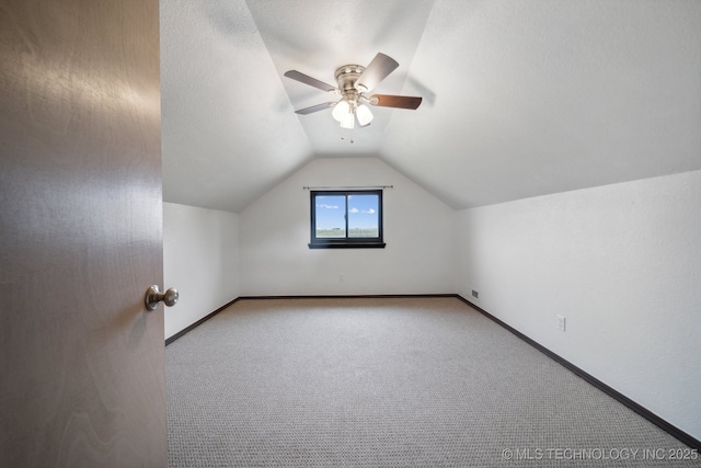 additional living space featuring light carpet, a textured ceiling, vaulted ceiling, and ceiling fan