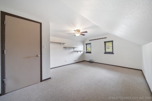 bonus room with vaulted ceiling, light colored carpet, ceiling fan, and a textured ceiling