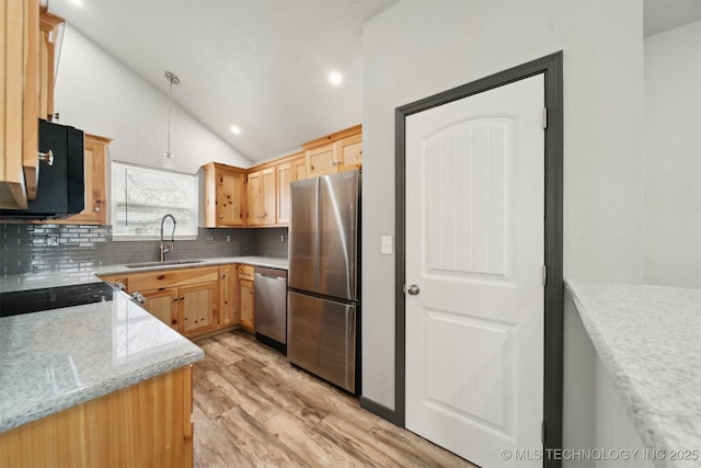 kitchen with sink, appliances with stainless steel finishes, light stone counters, decorative backsplash, and vaulted ceiling