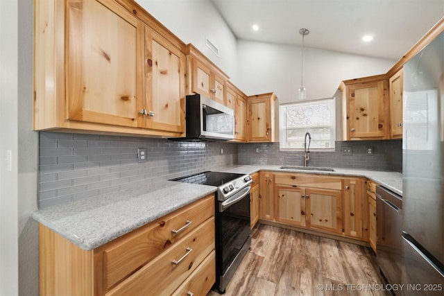 kitchen featuring lofted ceiling, sink, decorative light fixtures, stainless steel appliances, and light stone countertops