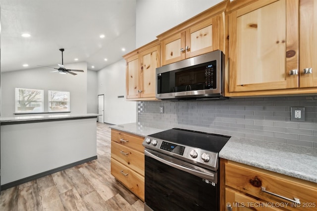 kitchen with vaulted ceiling, backsplash, light stone counters, ceiling fan, and stainless steel appliances