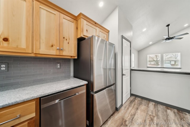 kitchen with lofted ceiling, backsplash, stainless steel appliances, light stone countertops, and light wood-type flooring