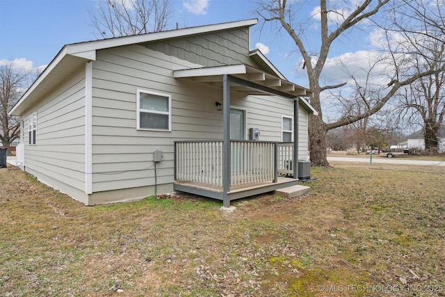 rear view of property featuring a yard, a deck, and central air condition unit