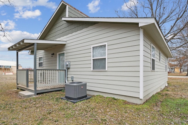 back of property with a wooden deck, a yard, and central AC