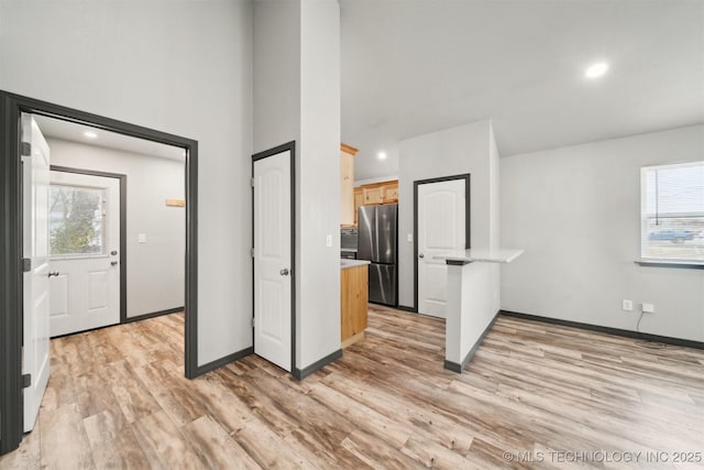 kitchen with light brown cabinetry, stainless steel fridge, and light hardwood / wood-style flooring