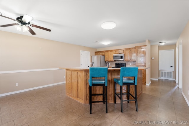 kitchen with sink, a breakfast bar area, tasteful backsplash, a center island with sink, and appliances with stainless steel finishes