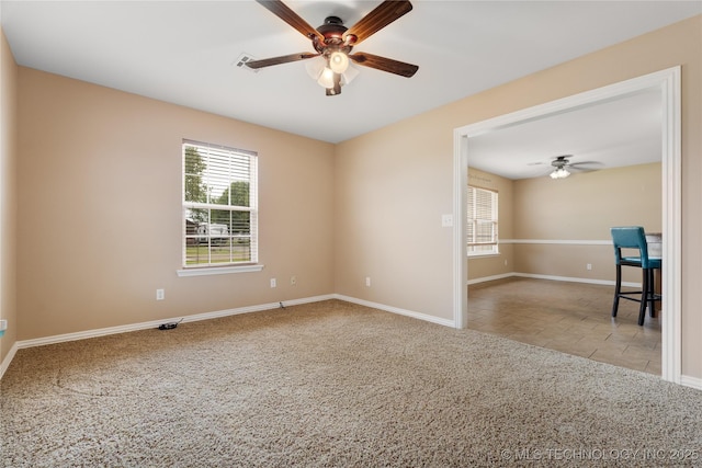 spare room with a wealth of natural light, light colored carpet, and ceiling fan