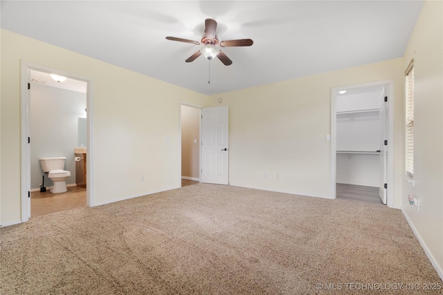 unfurnished bedroom with a closet, connected bathroom, a spacious closet, and carpet