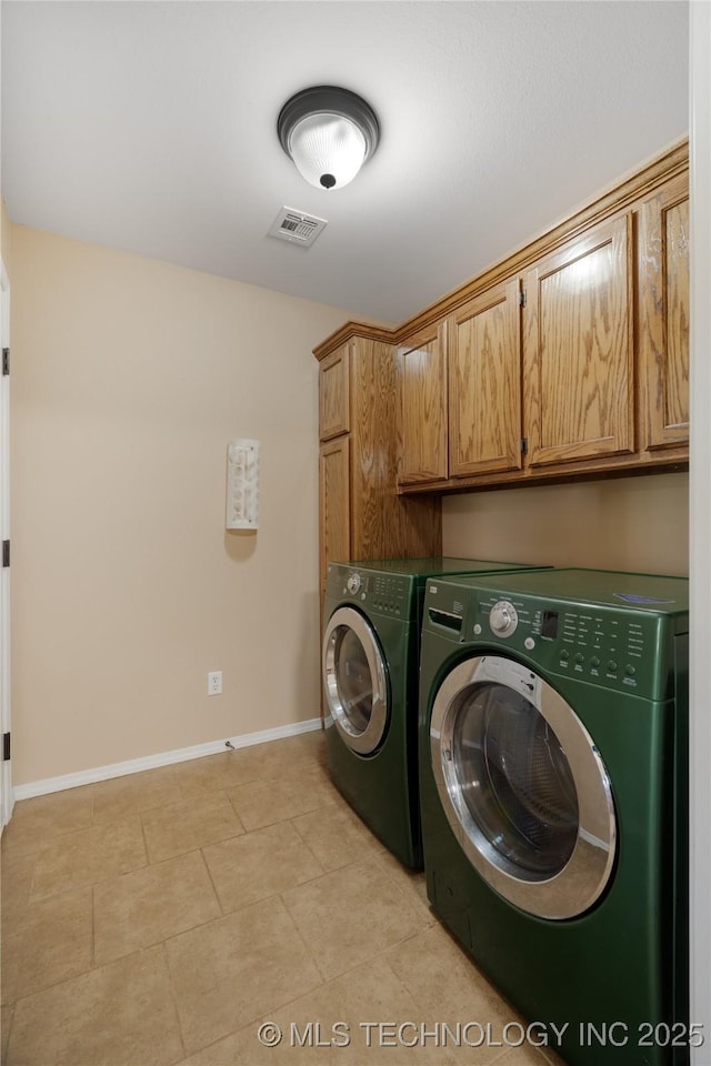 washroom with light tile patterned floors, cabinets, and washing machine and clothes dryer