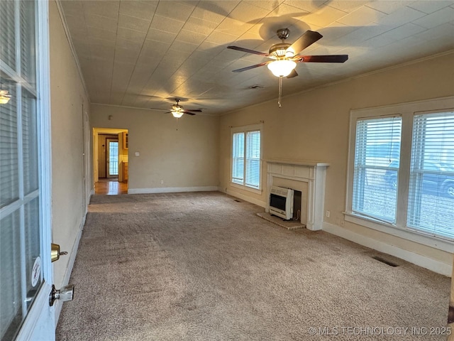 unfurnished living room featuring heating unit, crown molding, carpet floors, and ceiling fan