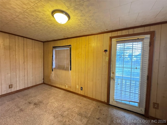 unfurnished room with crown molding, light carpet, and wood walls