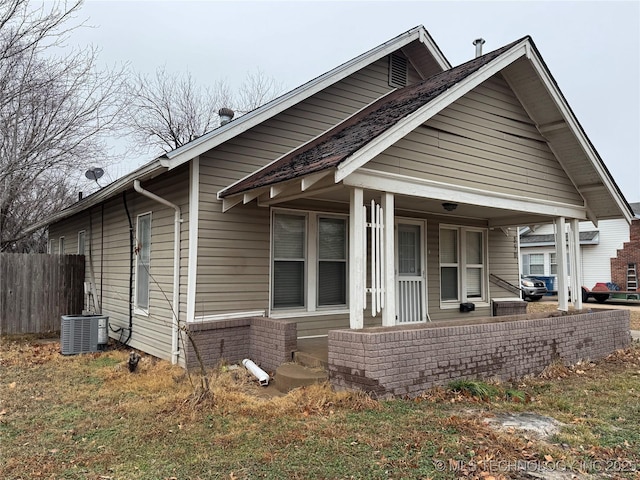 bungalow-style house with a porch and central AC unit